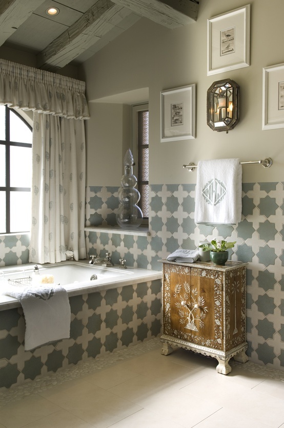 a neutral space with grey and white Moroccan tiles, a painted wooden sideboard and some artworks