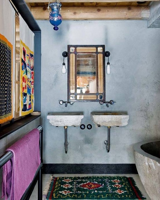 blue plaster walls, a concrete bathtub, printed rugs and curtains plus concrete sinks