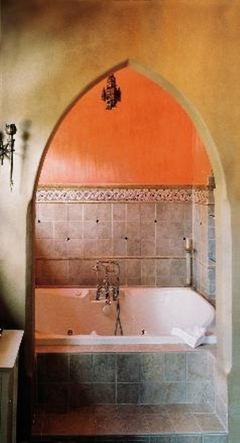 a colorful Moroccan bathroom done in sandy beige and orange with a tile clad bathtub