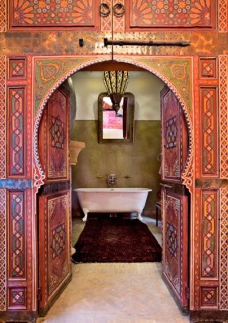 a super colorful Moroccan bathroom with red and blue patterned walls, a Moroccan lantern, green walls and a boho rug 