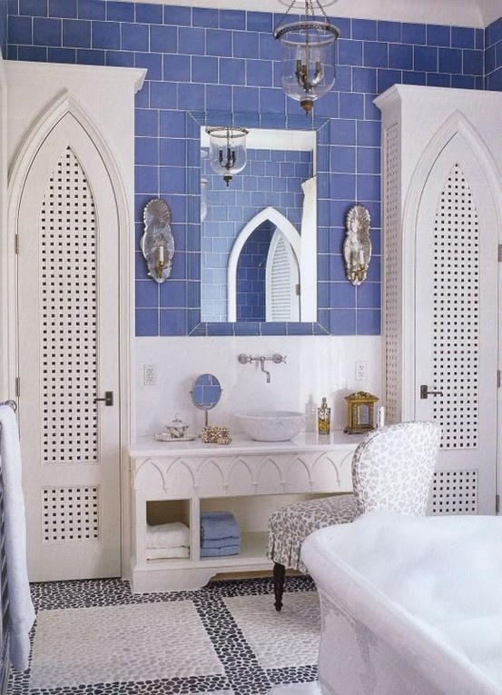 a purple and white bathroom with arched doorways, a pebble tile floor, a carved vanity and a glass lamp