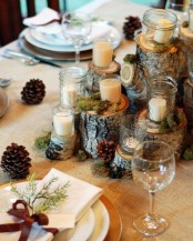 a chic and cozy rustic tablescape with tree stumps, candles and moss, pinecones and plates with greenery and brown bows, a burlap tablecloth