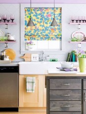 a lilac wall and matching shelves, a bright floral Roman shade plus lilac blooms make the kitchen look soft, tender and pastel-infused