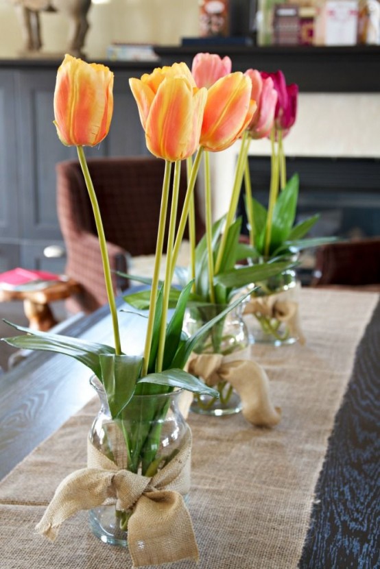 bright blooms in jars wrapped with burlap and with a burlap table runner make the tablescape spring-like