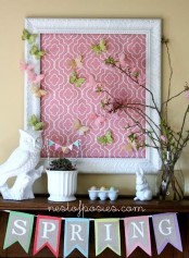 a bright and colorful spring mantel with an owl and a bunny, a colorful sign with butterflies, blooming branches and a succulent