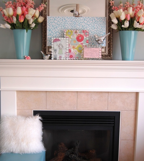 a colorful mantel with bright floral arrangements in blue vases and bright artworks