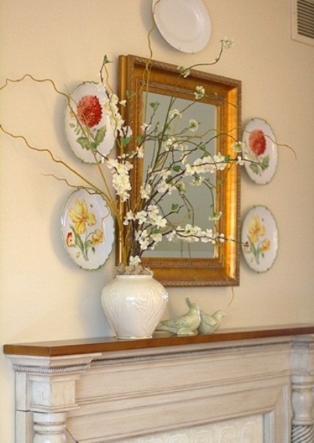 a vintage spring mantel with decorative plates and a faux blooming branch arrangement