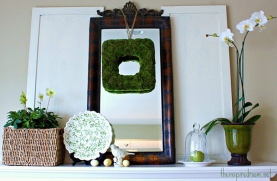 a rustic spring mantel with potted blooms, a moss wreath, faux eggs and a bird