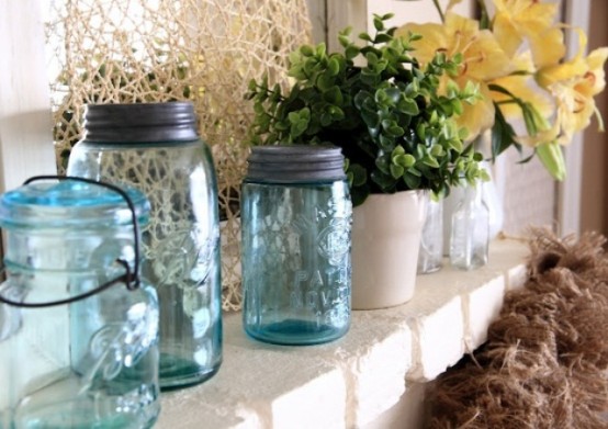 fresh blooms and greenery arrangements and blue jars create a spring feel on the mantel