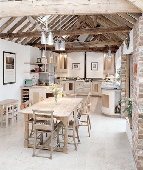 a modern natural kitchen with sleek white cabinetry, rough wooden beams and pendant lamps, a wooden dining set and chairs is very creative