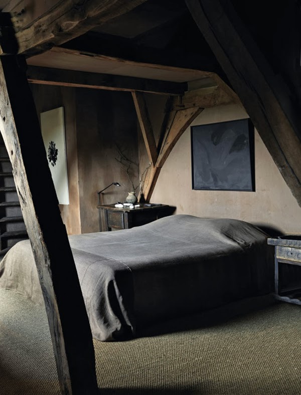 a moody bedroom in wabi sabi with wooden beams, rough wooden nightstands and artworks