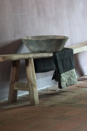 a rough wooden bench and a stone bowl plus a simple blanket for a wabi-sabi bathroom