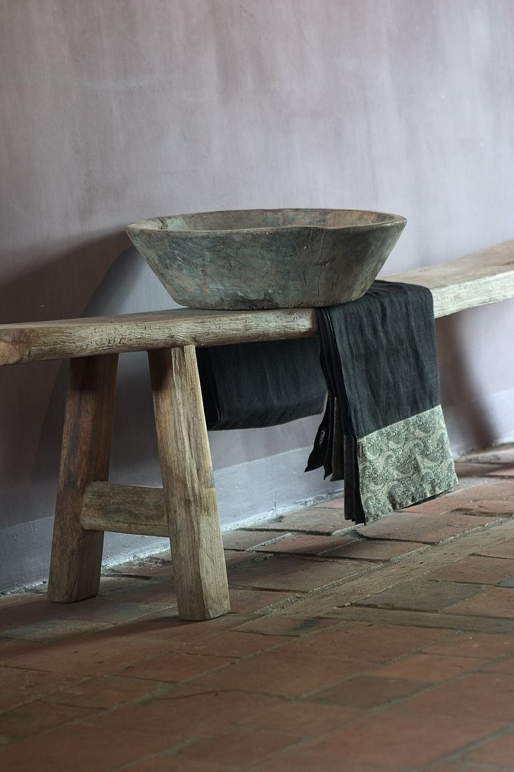 a rough wooden bench and a stone bowl plus a simple blanket for a wabi sabi bathroom