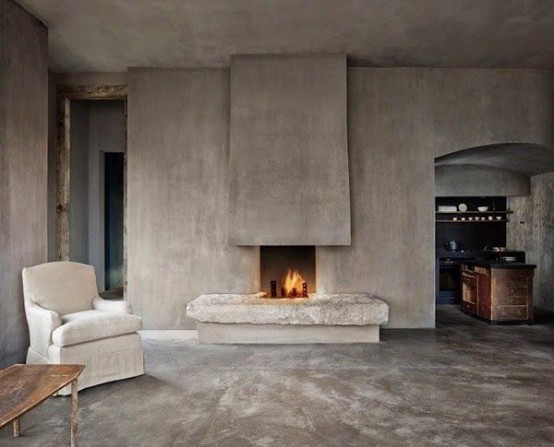 a wabi-sabi living room with concrete walls and a fireplace, a matching floor and very few furniture pieces
