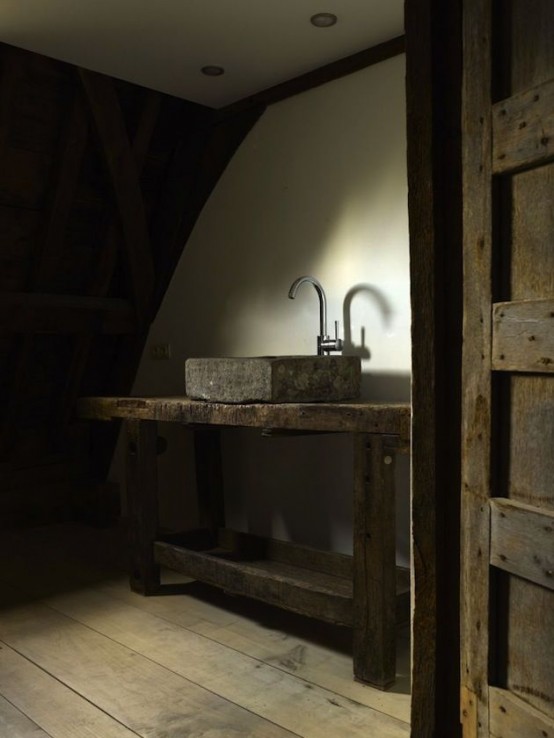 a wabi-sabi bathroom with a wooden vanity, a stone sink and bare walls for a minimalist and rough look