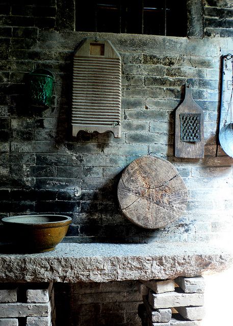a kitchen in wabi sabi style, with cutting boards, bowls and buckets and a hearth