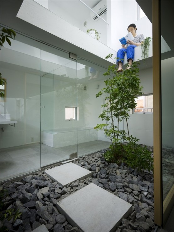 un patio japonés contemporáneo con guijarros, baldosas de piedra y un solo árbol que crece