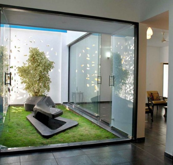 a minimal Japanese garden with grass, a tree and a creative and sculptural bench of stone