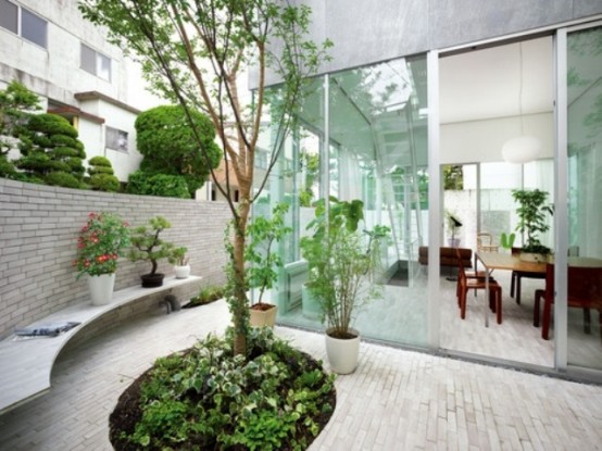 a minimalist Japanese-inspired courtyard with a tree and greenery, a bench and some bricks on the ground