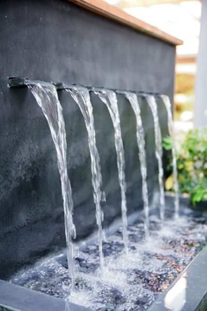 une fontaine moderne et élégante sortant du mur et tombant dans un bol avec des galets est une belle idée pour un espace moderne ou minimaliste une fontaine moderne et élégante sortant du mur et tombant dans un bol avec des galets est une belle idée pour un espace moderne ou minimaliste
