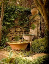 a creative stone fountain of a stone stella, a couple of stone bowls surrounded with moss and greenery for a vintage-infused garden