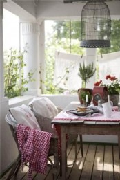 a cute summer porch with rattan and wood furniture, bright printed textiles, greenery and a suspended cage