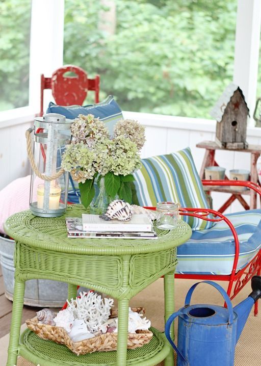 a colorful summer porch done in green and blue, with touches of red, candle lanterns and blooms
