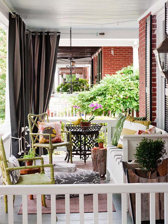 a colorful summer porch with yellow rattan chairs, a white bench, tree stump tables and bright textiles