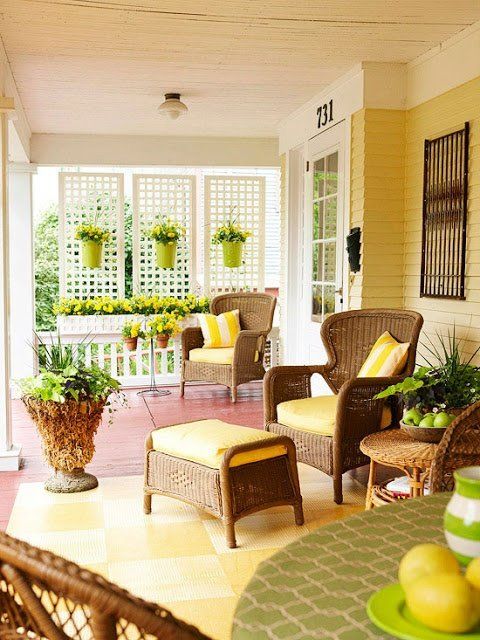 a bright summer porch with wicker furniture, sunny yellow textiles and accessories plus lots of potted flowers and greenery
