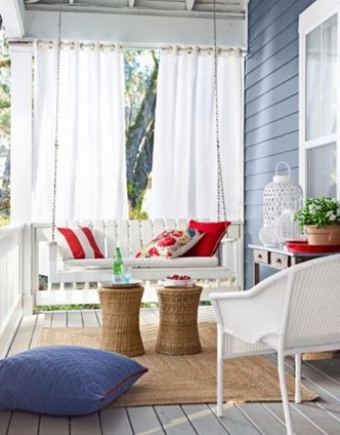 a bright summer porch with white wicker furniture, colorful pillows and white candle lanterns