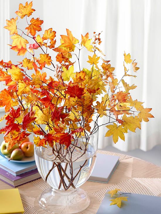 a modern fall centerpiece of a clear glass vase and lots of bold fall leaves is very chic
