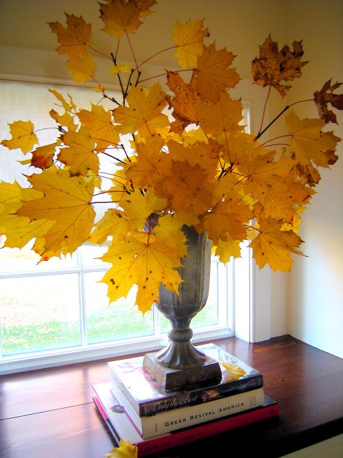 a refined vintage urn with lots of bright yellow fall leaves is a cool fall centerpiece or just decoration