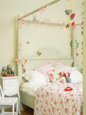 a pastel green girl’s bedroom with a canopy bed decorated with blooms, floral bedding, bold hearts, toys and just decor is romantic and pretty