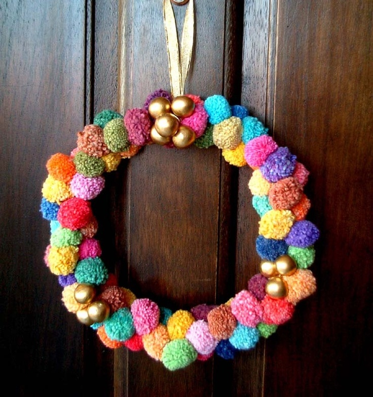 a colorful pompom wreath with gold ornnaments is a nice idea for Christmas or New Year and it will bring much color