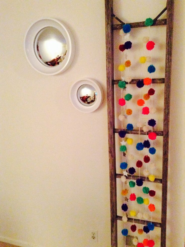 hang some colorful pompoms on a ladder to make your space more bright and fun without much effort