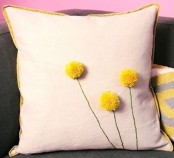 a neutral pillow with gold edges with yellow pompoms that imitate billy balls is a nice accessory for spring