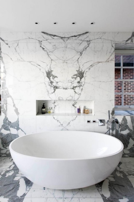 a bright contemporary bathroom done with white and grey tiles, amodern oval tub and windows