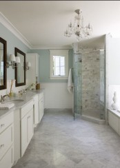 a modern farmhouse bathroom with aqua walls, neutral vanities, a shower space with marble tiles and floor