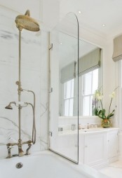 an elegant bathroom done in creamy, with vintage hardware and white marble in the tub zone