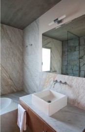a unique bathroom pairign marble and stone, with a floating vanity and a square sink plus a mirror