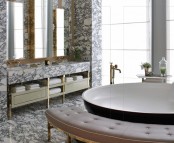 a unique bathroom with a round tub, a pink curved bench, a built-in vanity and much black and white marble