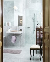 a neutral eclectic bathroom done with white marble tiles, a shower space, a sink and a tub plus dark stained furniture