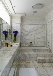 a gorgeous neutral marble bathroom with a floating vanity, a sink and a mirror plus a large bathing space