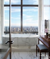 a fantastic bathroom with dark stained furniture and a tub clad with white marble plus a gorgeous and breathtaking view