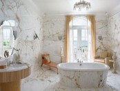a quirky bathroom done with unique marble, an oval tub, a sink in a creative holder and some upholstered furniture