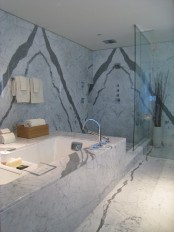 a modern bathroom with grey marble, a bathtub, a shower space looks chic and bold