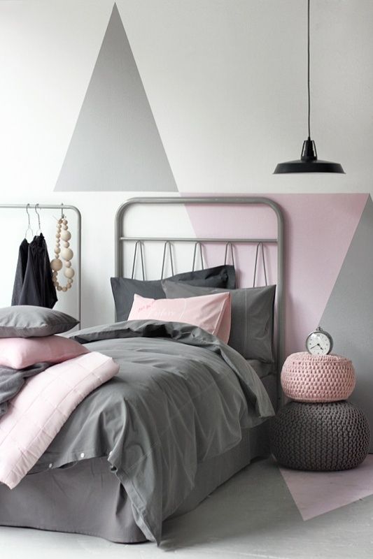 a Scandinavian kid's room with grey and pink geometric decor on the wall, grey beds, grey and pink bedding