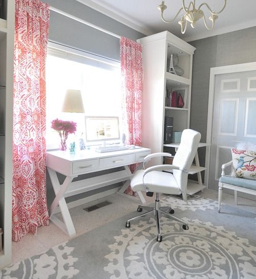 a vintage grey home office with white furniture, pink printed curtains, a grey printed rug and some pillows