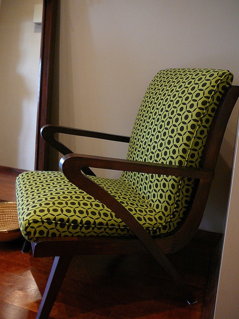 a mid century modern chair with a dark stained frame, armrests and legs and bright printed upholstery will make a statement with color