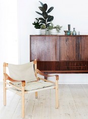 a lovely mid-century modern chair with a light-stained frame and legs, with leather touches and neutral upholstery